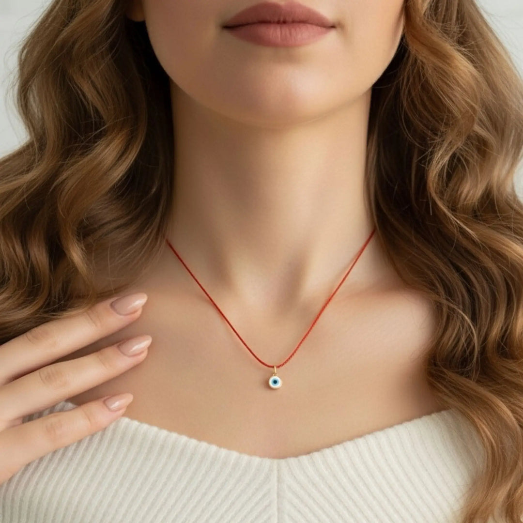 Woman wearing a red necklace with an evil eye pendant
