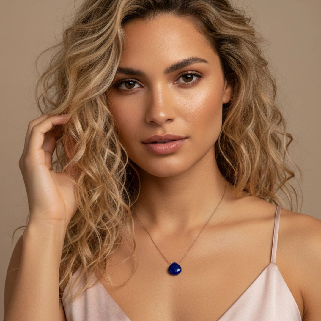 Woman wearing a necklace with a lapis lazuli pendant against a beige background