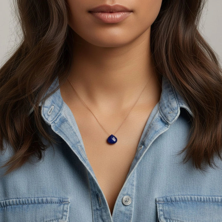 Person wearing a lapis lazuli  pendant necklace with a denim shirt