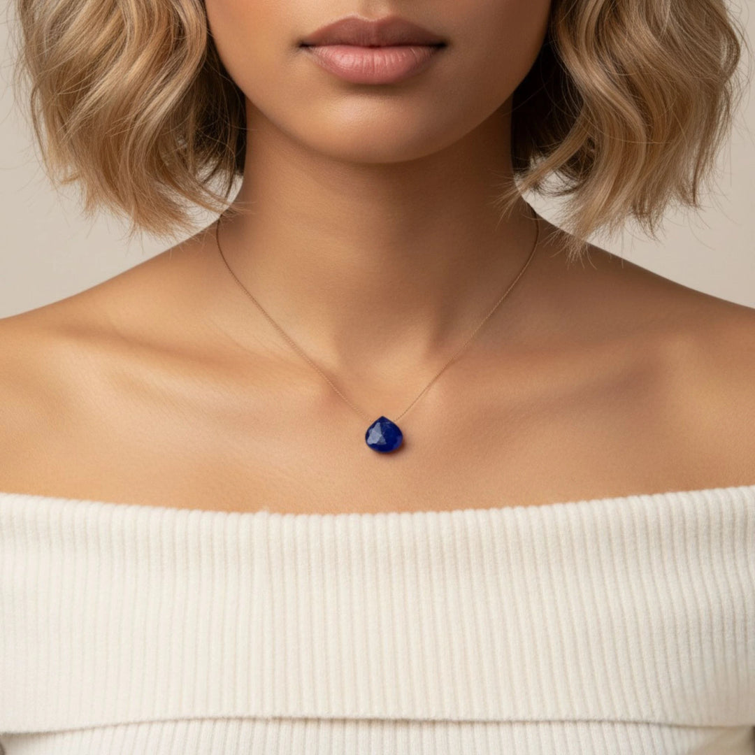 Woman wearing a necklace with a lapis lazuli pendant on a neutral background