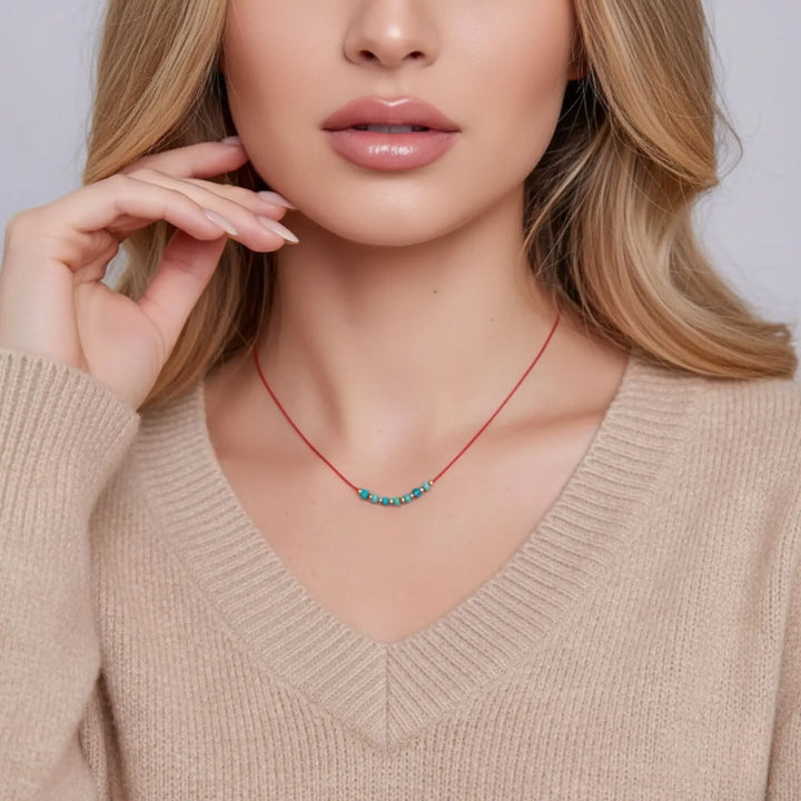 Woman wearing a red necklace with small beads against a neutral background