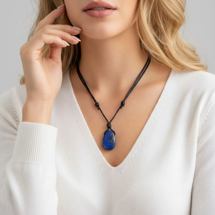 Woman wearing a necklace with a blue lapis lazuli pendant against a neutral background