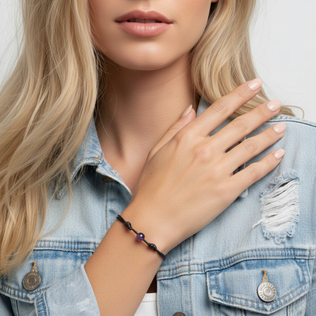 Woman wearing smooth amethyst round bead bracelet on black waxed nylon cord.