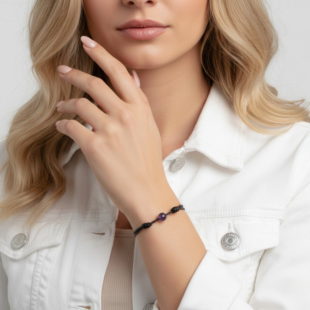 Woman wearing smooth amethyst single bead bracelet on black waxed nylon cord.
