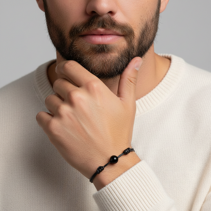 Man wearing smooth black gemstone single bead bracelet on black waxed nylon cord.
