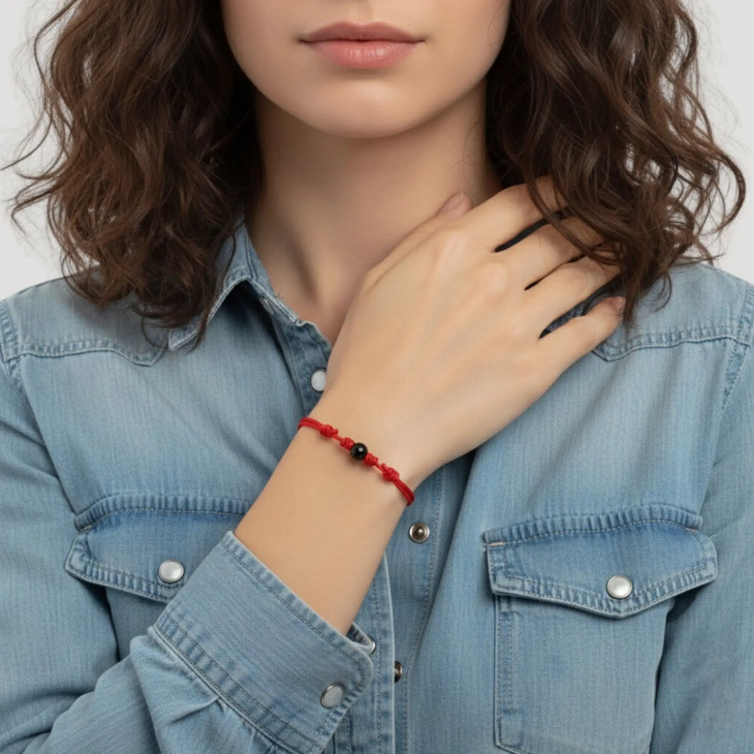 Woman wearing smooth black tourmaline round bead bracelet on red nylon cord.