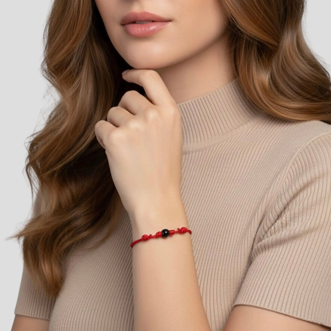 Woman wearing smooth black tourmaline round bead bracelet on red nylon cord.