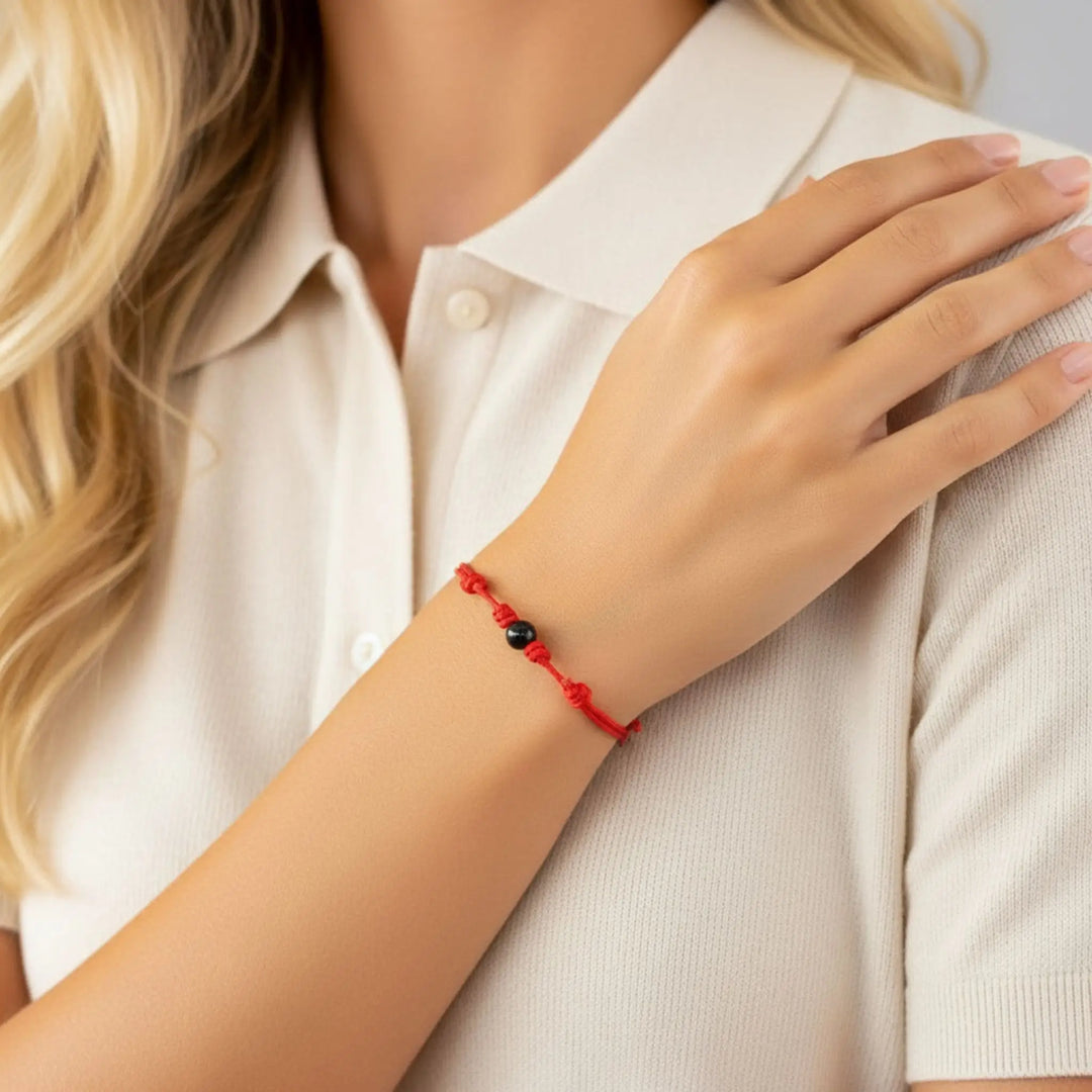 Woman wearing smooth black tourmaline round bead bracelet on red nylon cord.