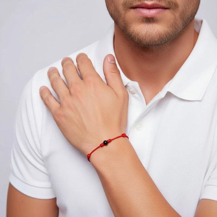 Man wearing smooth black tourmaline single bead bracelet on red waxed nylon cord.
