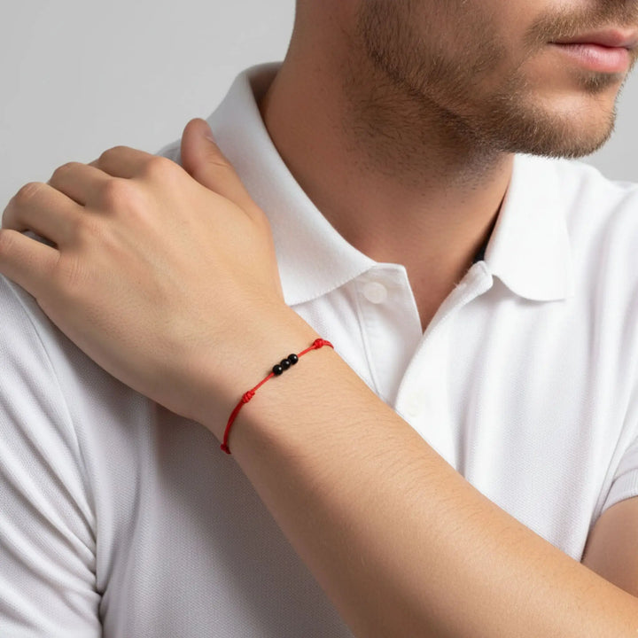 Man wearing smooth black tourmaline triple bead bracelet on red waxed nylon cord.
