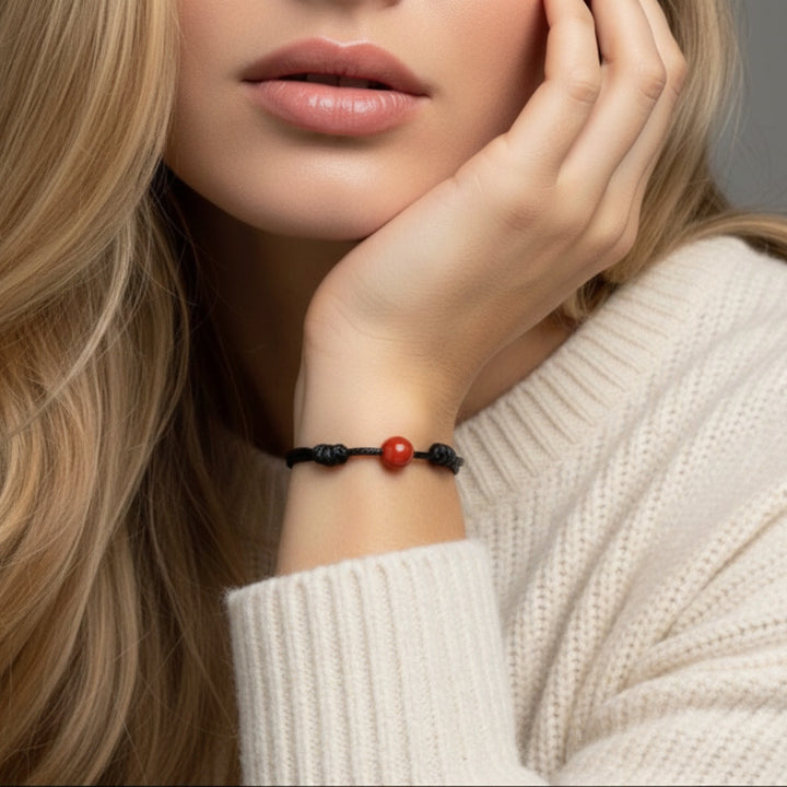 Woman wearing smooth carnelian single bead bracelet on black waxed nylon cord.
