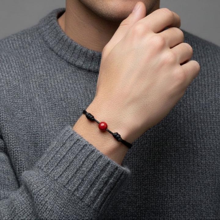 Man wearing smooth carnelian single bead bracelet on black waxed nylon cord.
