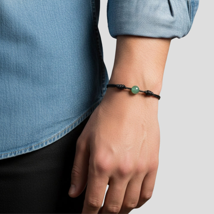 Man wearing smooth green aventurine single bead bracelet on black waxed nylon cord.
