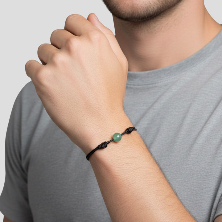 Man wearing smooth green aventurine single bead bracelet on black waxed nylon cord.
