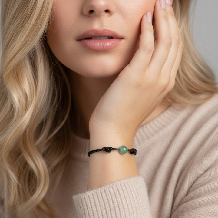 Woman wearing smooth green aventurine single bead bracelet on black waxed nylon cord.
