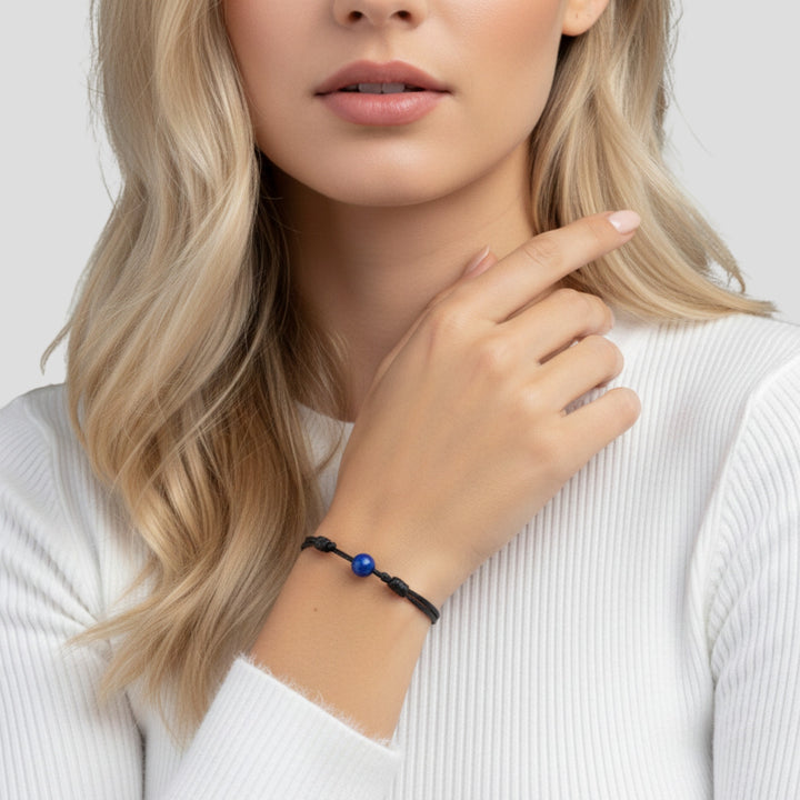 Woman wearing smooth lapis lazuli single bead bracelet on black waxed nylon cord.
