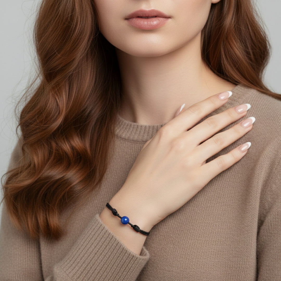 Woman wearing smooth lapis lazuli single bead bracelet on black waxed nylon cord.
