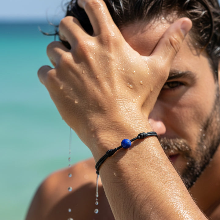 Man wearing smooth lapis lazuli single bead bracelet on black waxed nylon cord.
