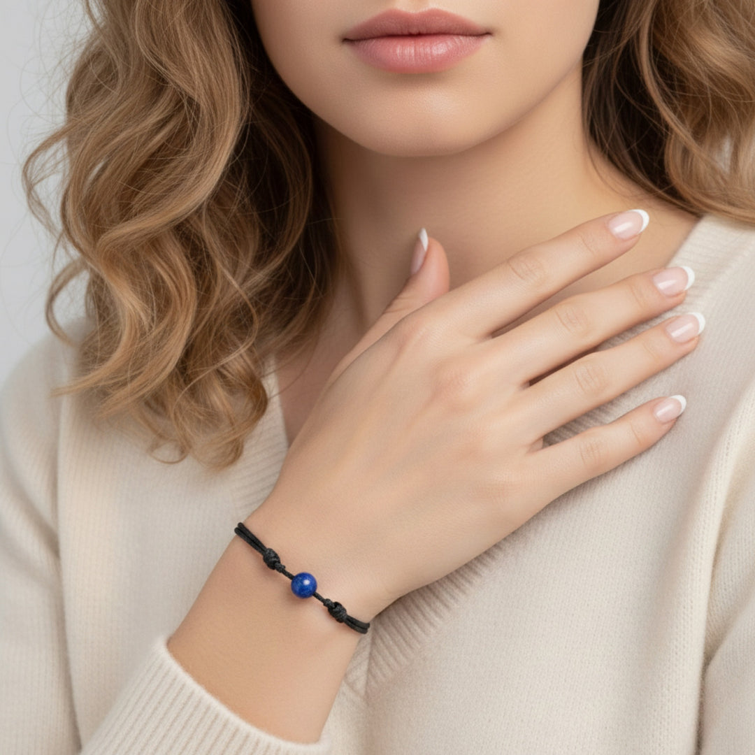 Woman wearing smooth lapis lazuli single bead bracelet on black waxed nylon cord.
