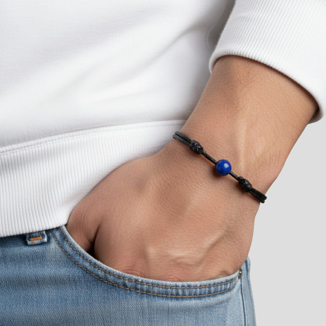 Man wearing smooth lapis lazuli single bead bracelet on black waxed nylon cord.
