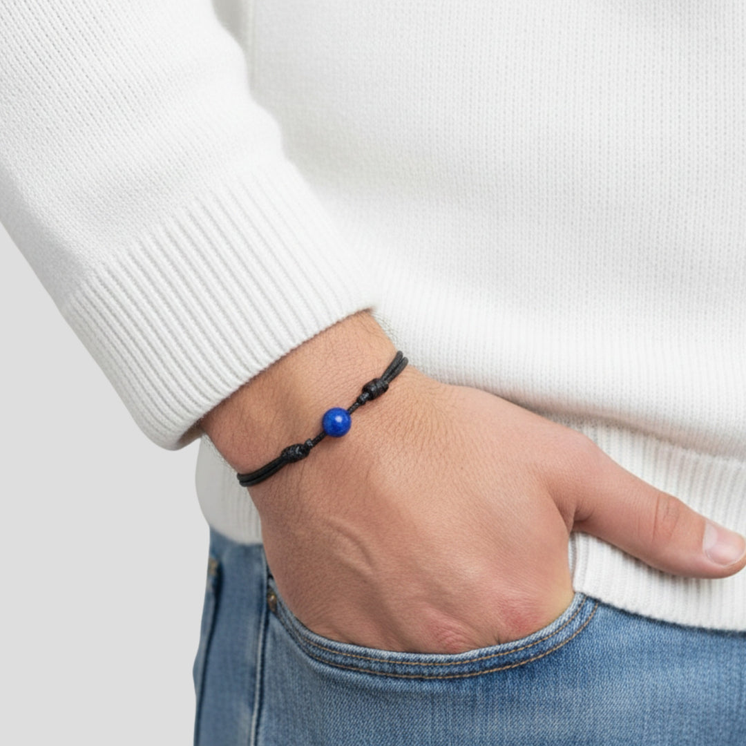 Man wearing smooth lapis lazuli single bead bracelet on black waxed nylon cord.
