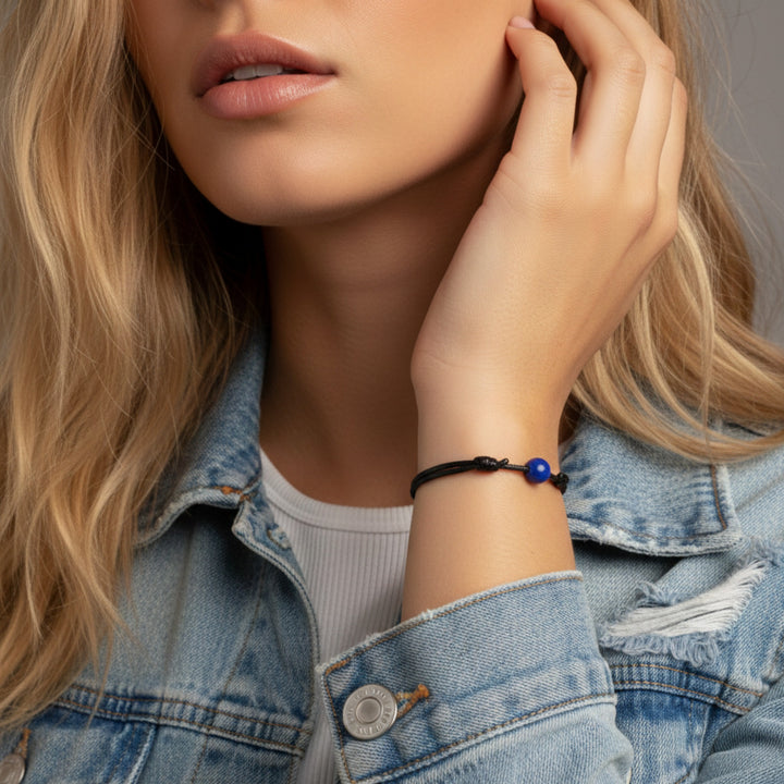 Woman wearing smooth lapis lazuli single bead bracelet on black waxed nylon cord.
