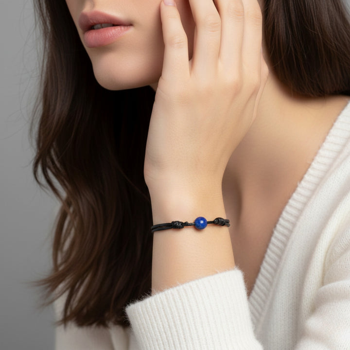 Woman wearing smooth lapis lazuli single bead bracelet on black waxed nylon cord.
