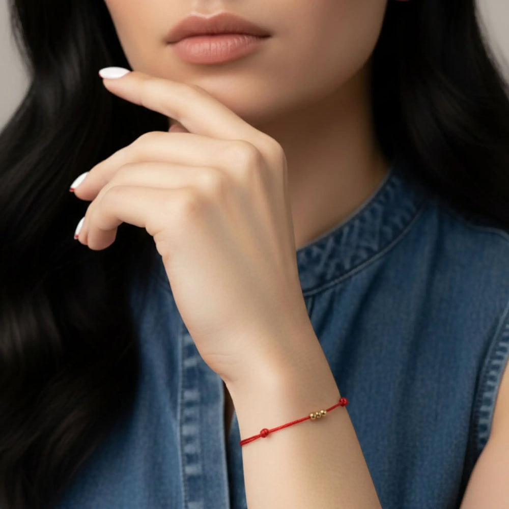 Close-up of a woman's hand wearing a red bracelet with a blurred background