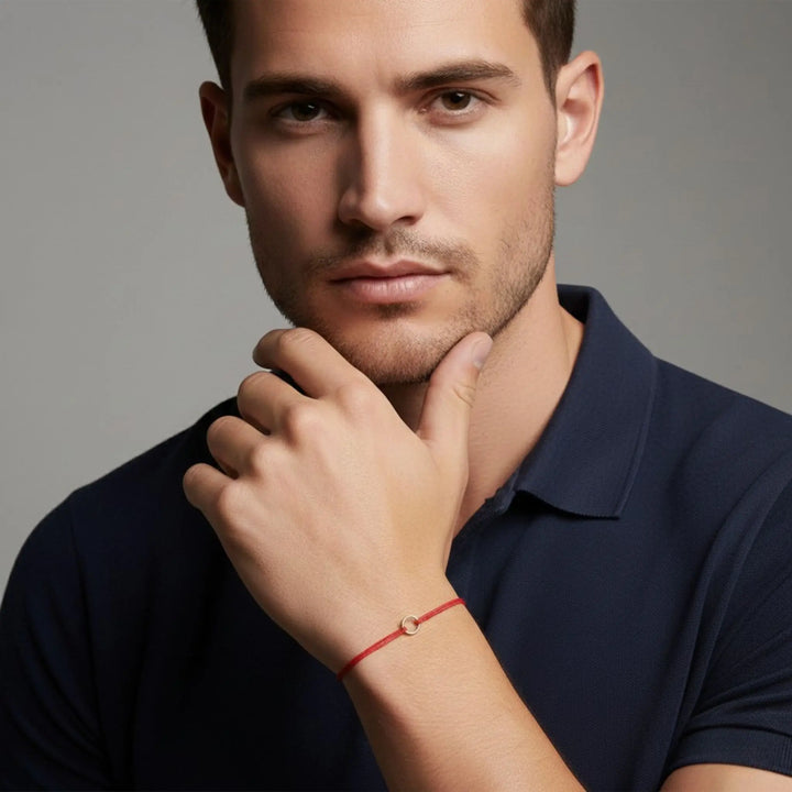 Man wearing a navy blue polo shirt with a red bracelet on a gray background