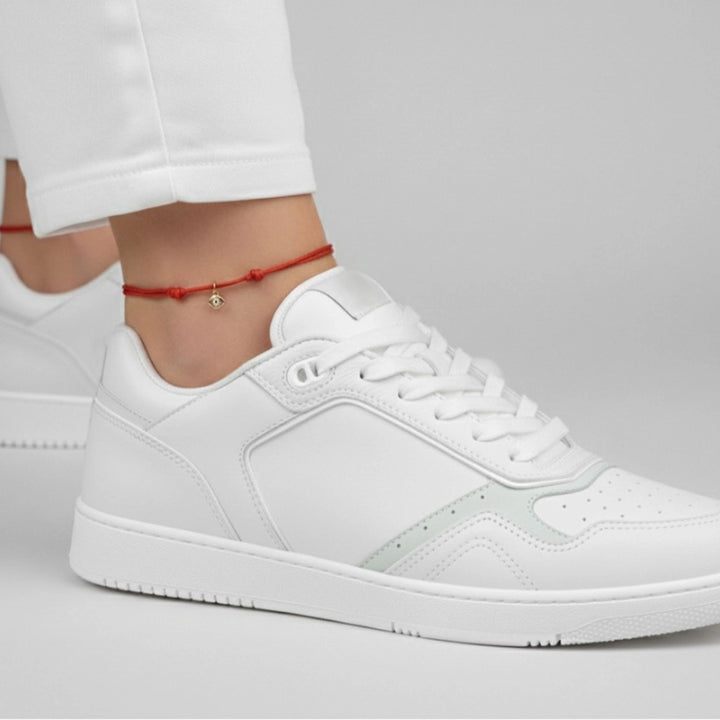 White sneaker worn with a plain background