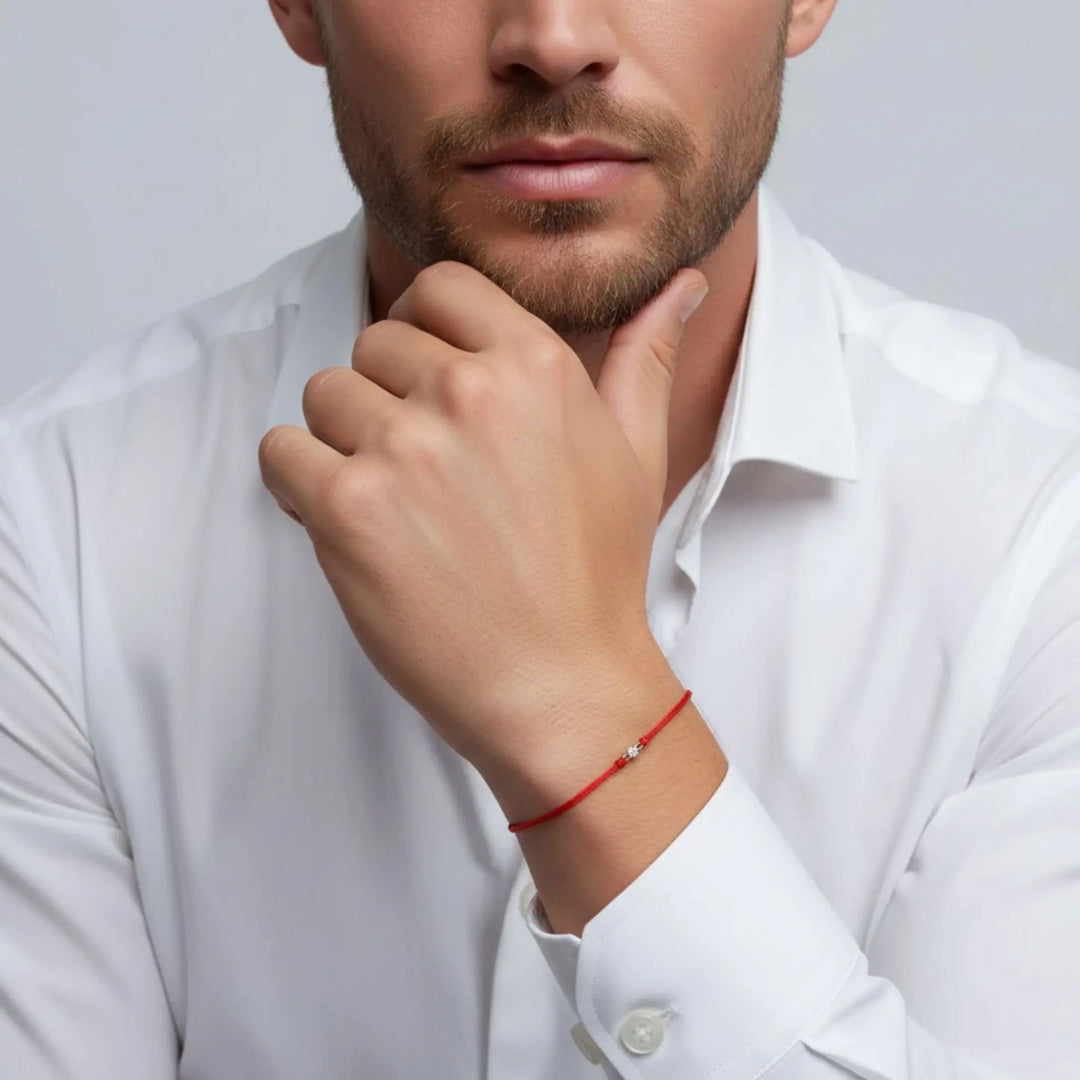 Man wearing a white shirt with a gold diamond red bracelet on a gray background