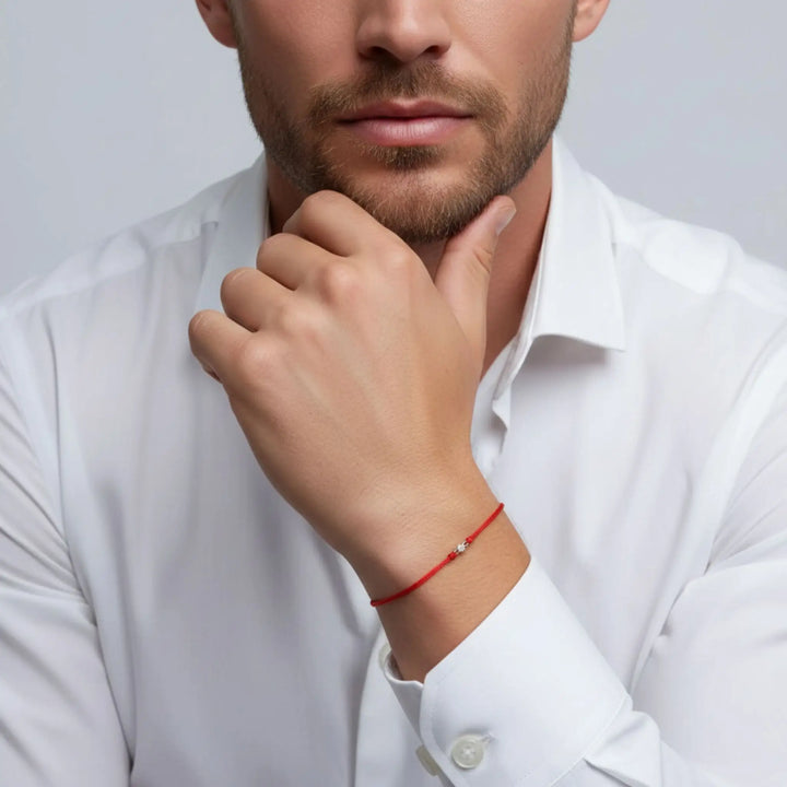 Man wearing a white shirt with a gold diamond red bracelet on a gray background