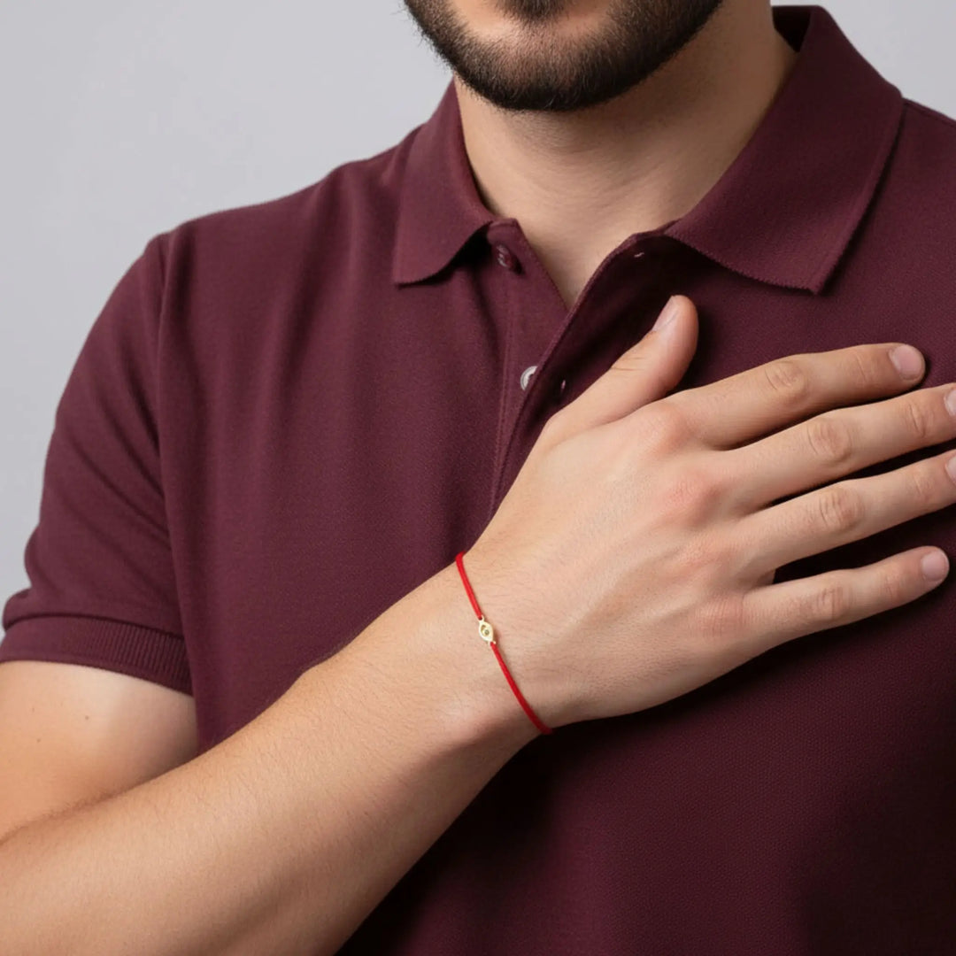 Man wearing a maroon polo shirt with a gold evil eye red bracelet on his wrist.