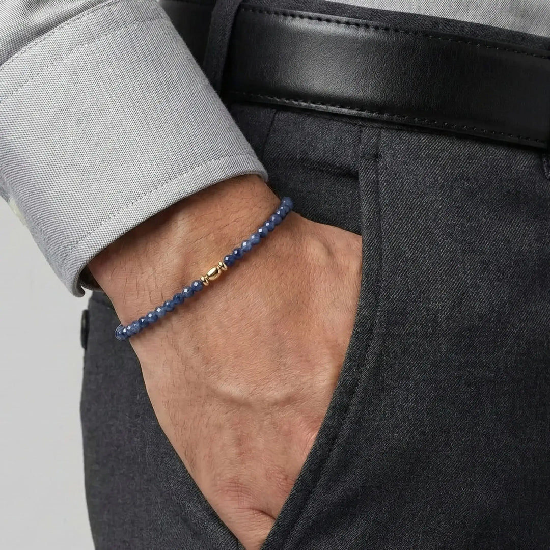 Close-up of a person wearing a blue sapphire beaded bracelet with a gold clasp.