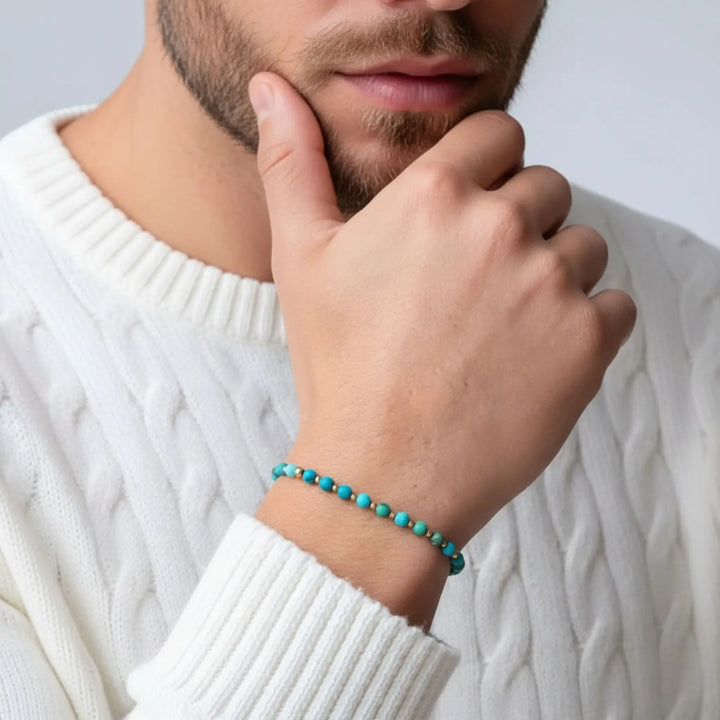 Person wearing a turquoise beaded bracelet on a white sweater