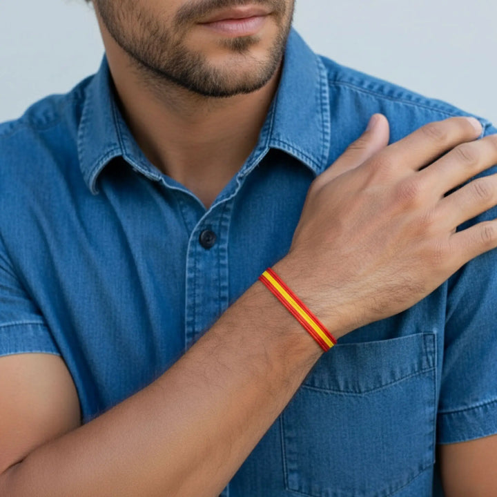 Man wearing a blue shirt with a red and yellow bracelet on his wrist.