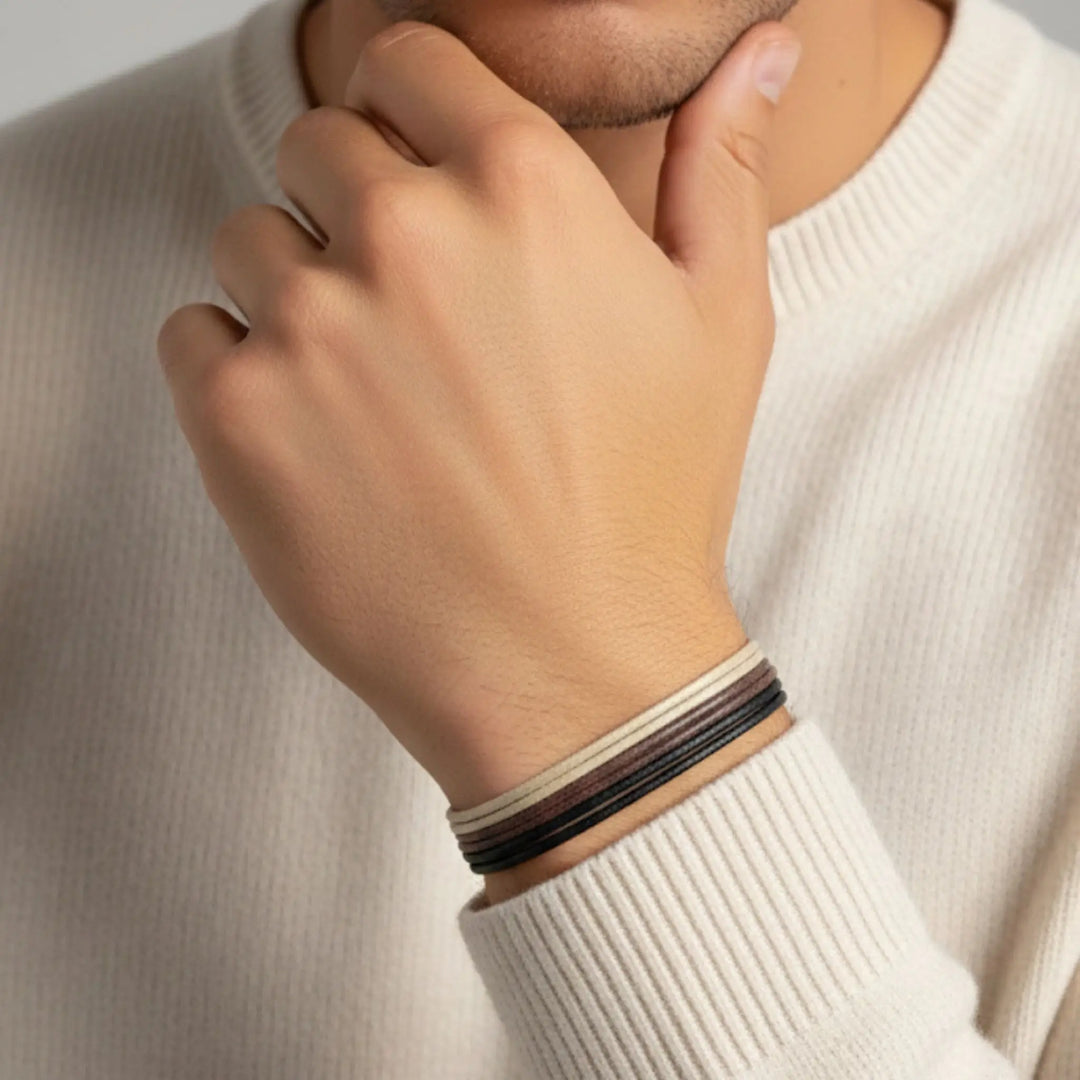Person wearing a striped bracelet on a neutral background