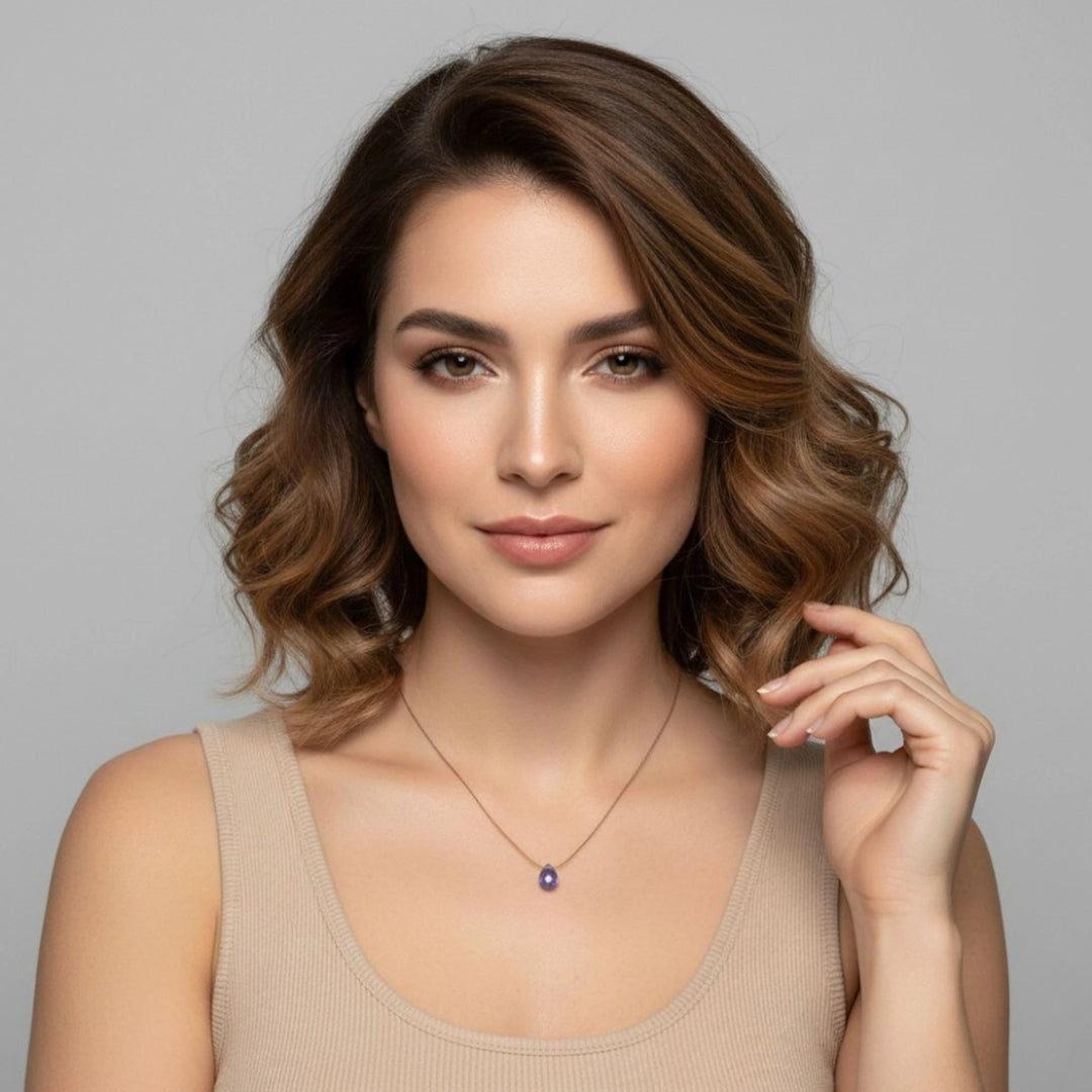 Woman wearing a necklace with a tanzanite pendant against a gray background