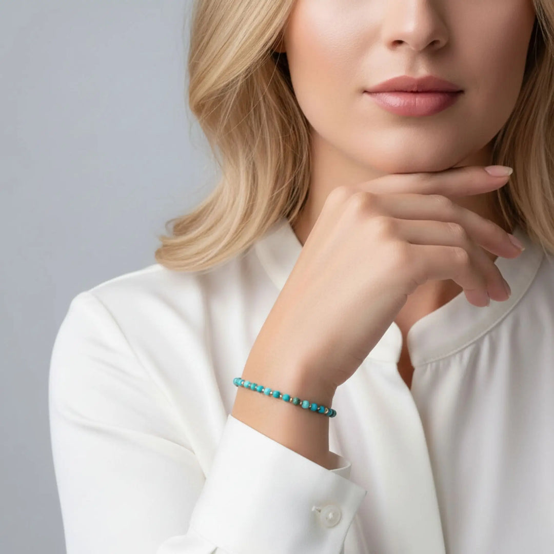 Woman wearing a turquoise bracelet on a plain background