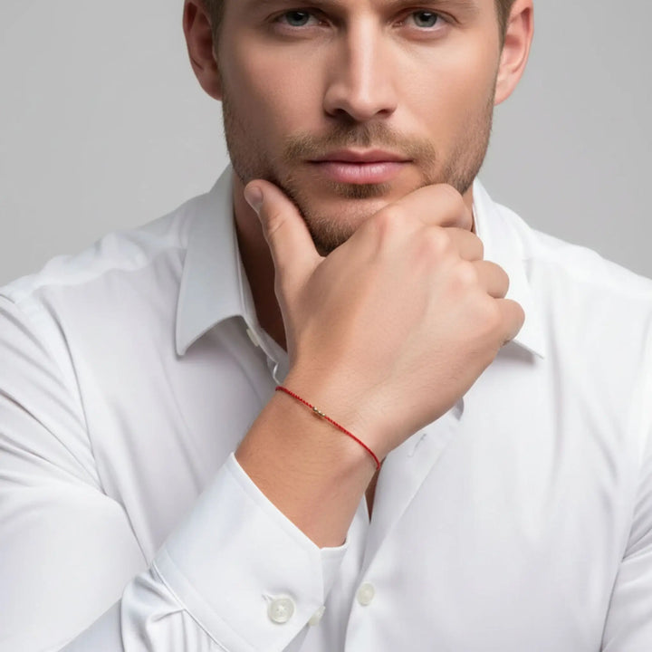 Man wearing a white shirt with a red bracelet on a gray background