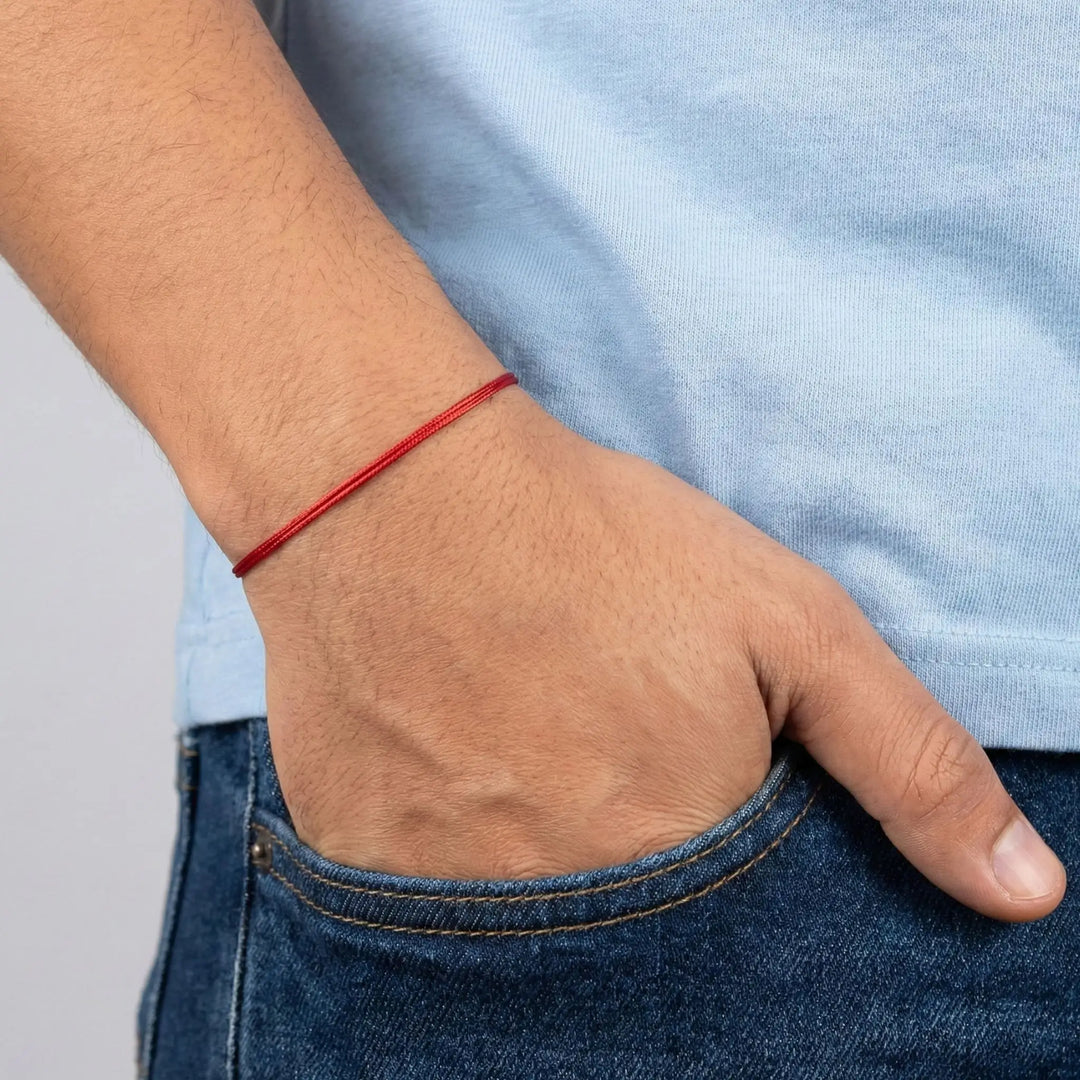 Hand with a red bracelet on a plain background