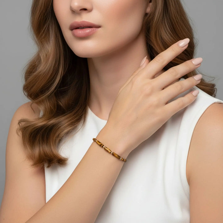 Woman wearing a gold bracelet on a neutral background