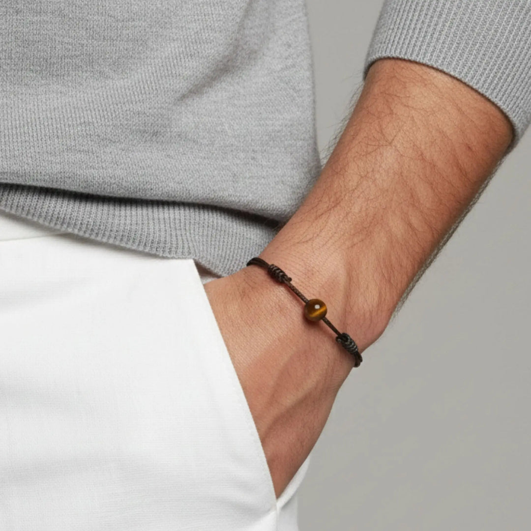 Close-up of a wrist wearing a tiger eye bracelet with a neutral background