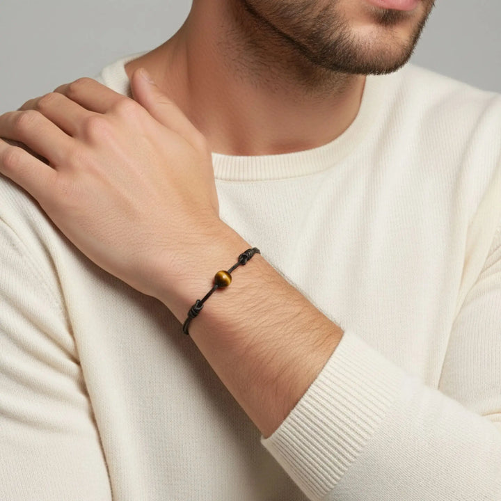 Minimalist tiger’s eye bracelet on waxed nylon cord worn by man in neutral outfit