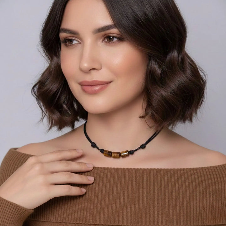 Woman wearing a tigers eye necklace with a plain background
