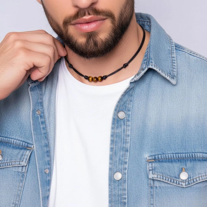 Man wearing a denim jacket and a necklace with a plain background