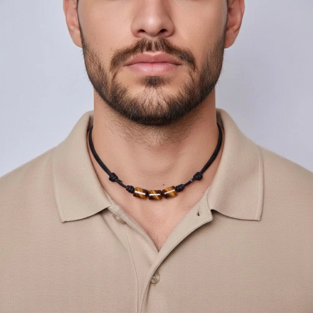 Man wearing a tigers eye necklace with a neutral background