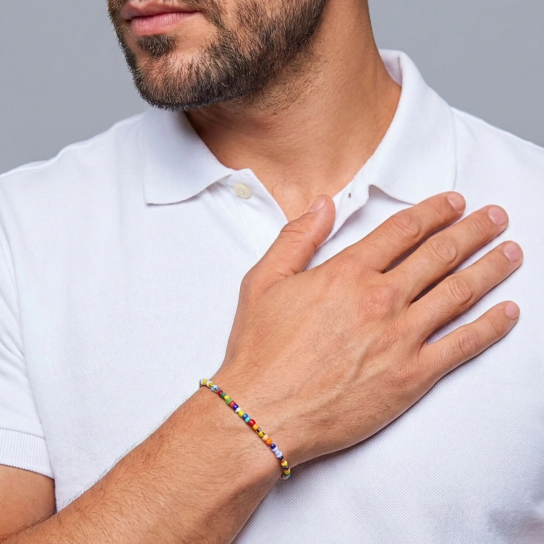 Man wearing a colorful beaded bracelet on his wrist, with a neutral background