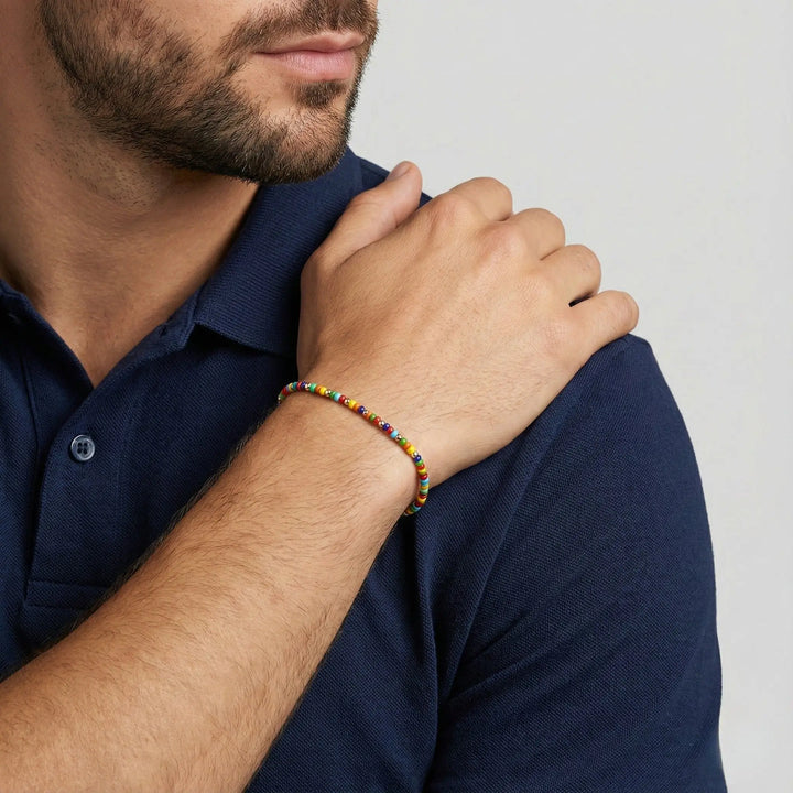 Man wearing a colorful beaded bracelet on his wrist, with a neutral background