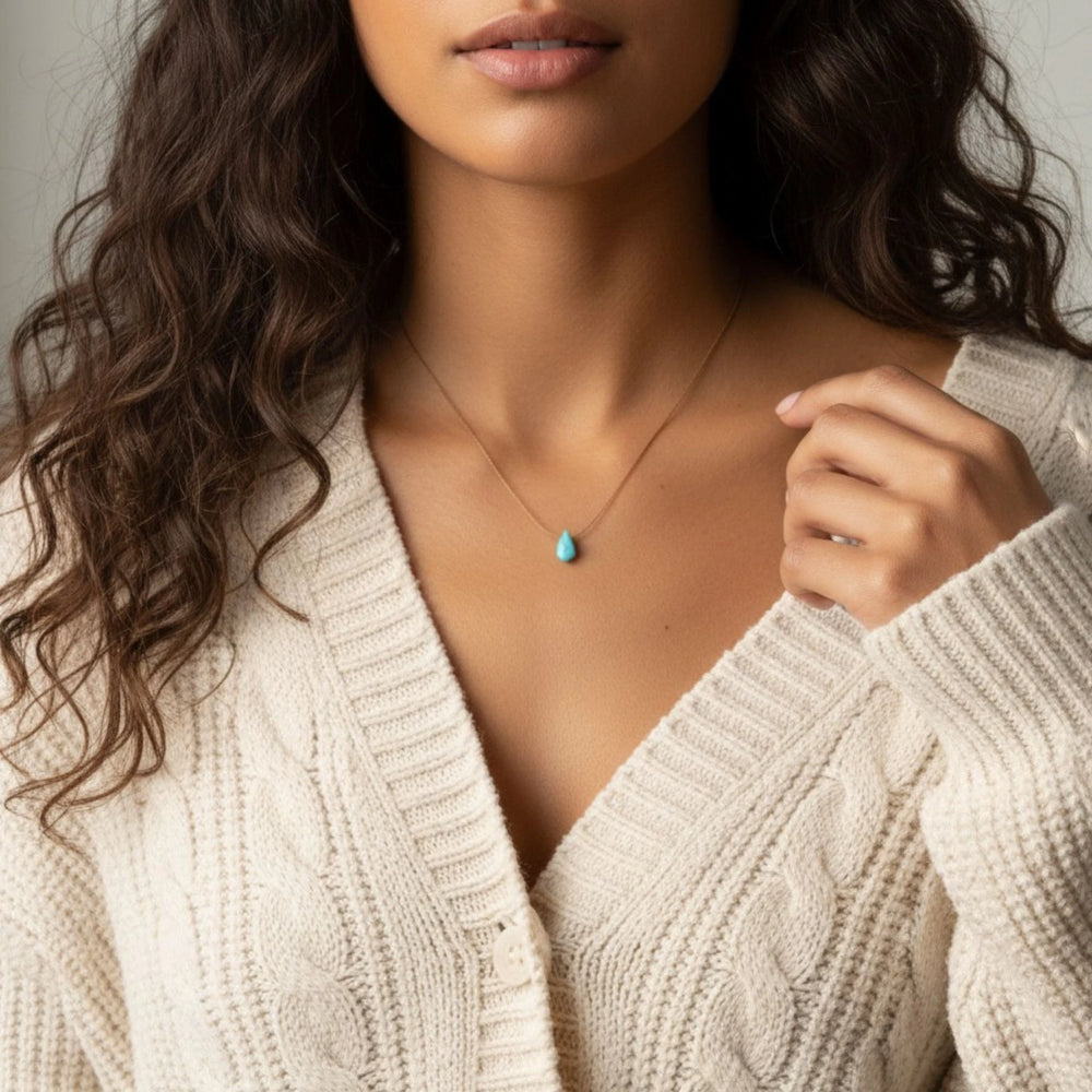 Woman wearing a white knitted cardigan with a turquoise necklace